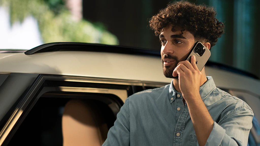 Personne debout à côté d’un véhicule MINI tout en parlant au téléphone portable.