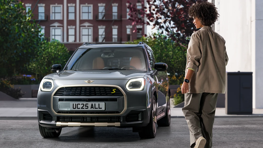 Personne utilisant un smartphone devant un MINI Countryman avec toit blanc.